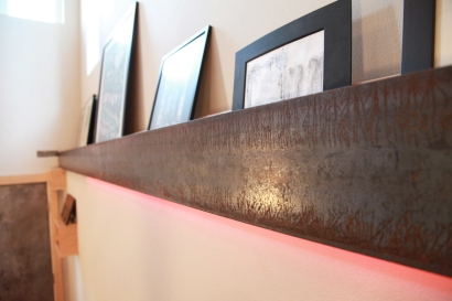 A steel beam required for retrofitting the structure becomes an art shelf and lighting element at the entry.